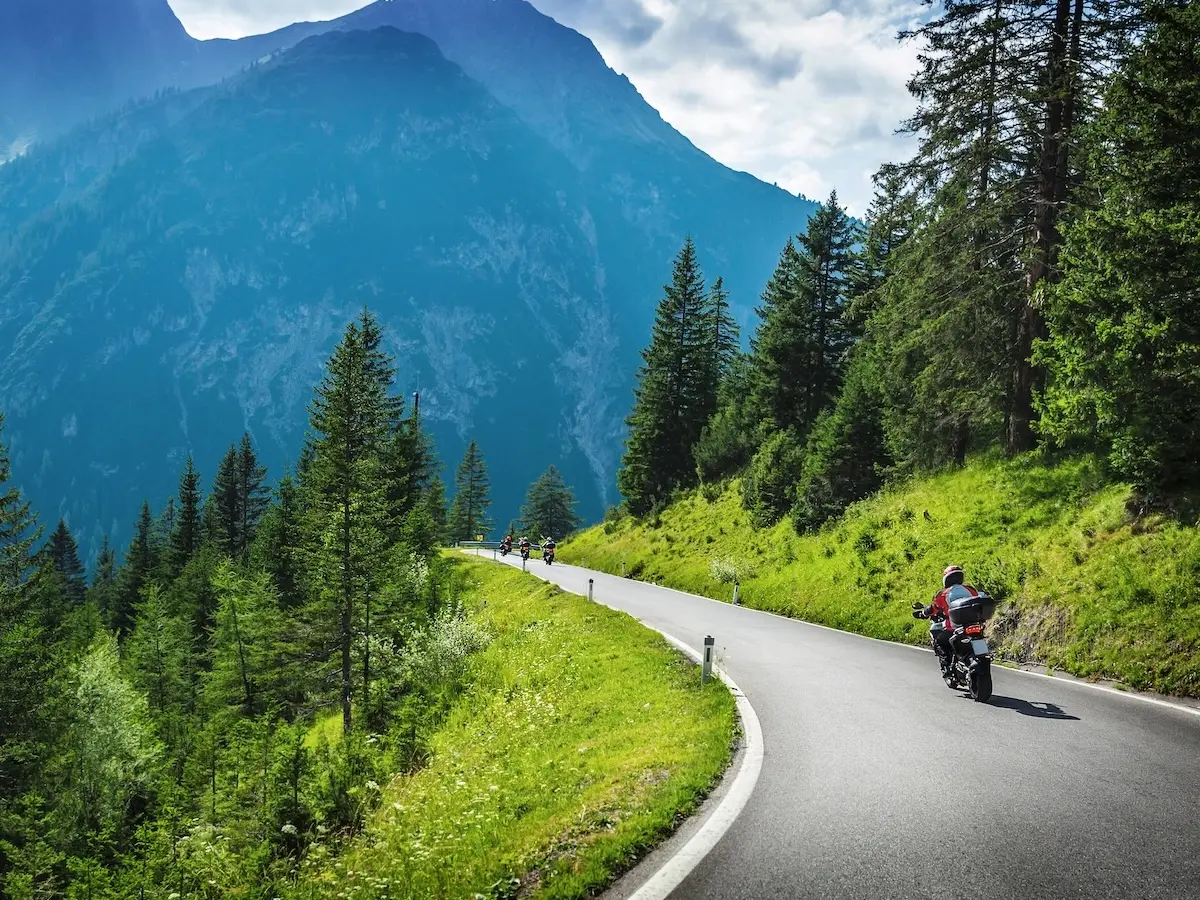 Motorradfahrer auf einer kurvigen Passstraße in Südtirol mit Bergpanorama – geführte Alpentour über das Penser Joch.
