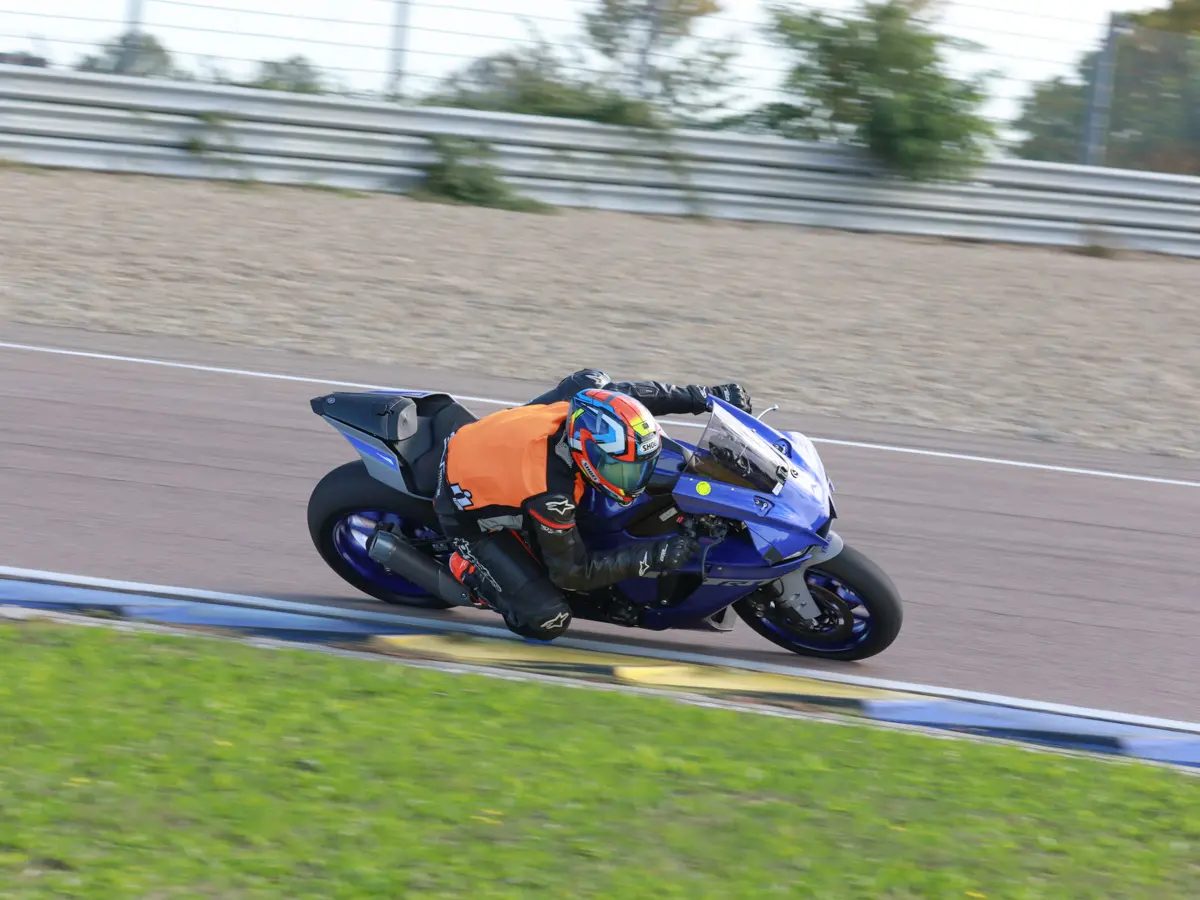 An instructor on a blue Yamaha R1 demonstrates correct vision and line choice in a corner.