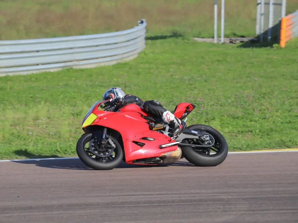 Nahaufnahme eines Ducati-Fahrers in voller Lederkombi und Schräglage auf der Rennstrecke.