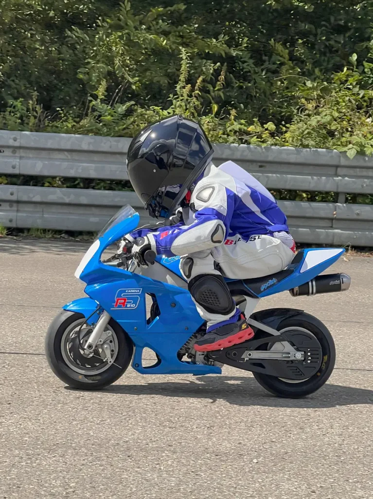 Früh übt sich: Ein junges Talent trainiert in voller Schutzausrüstung und sportlicher Haltung auf einem Polini Pocketbike.