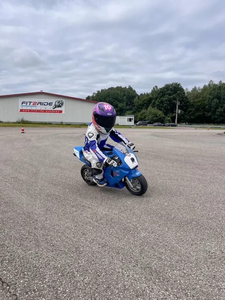 Kind in voller Schutzausrüstung lernt das Motorradfahren auf einem Pocketbike bei der Fit2Ride Academy.