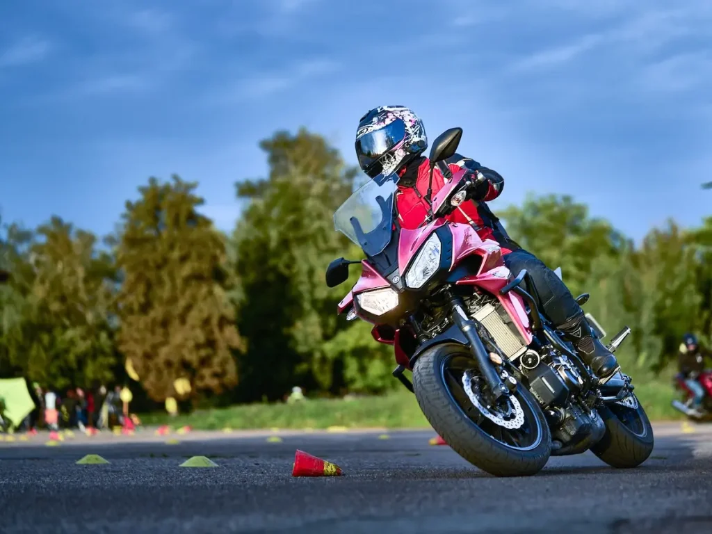 Motorradfahrerin in Schutzkleidung fährt Slalom um Pylonen beim Fahrsicherheitstraining.