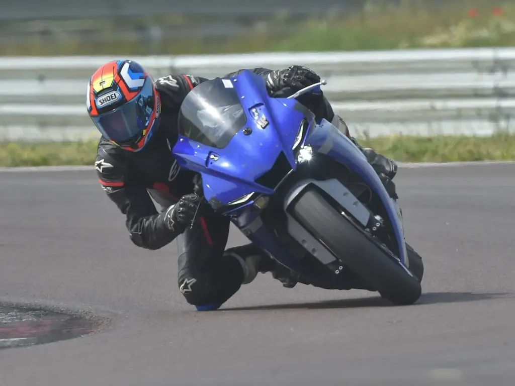 Motorradfahrer auf einer blauen Yamaha beim Rennstreckentraining in extremer Schräglage mit Hang-Off-Technik.